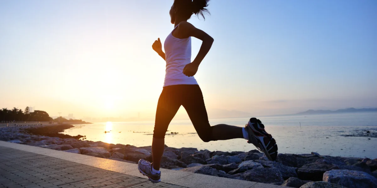 Woman running on a coastal path at sunset